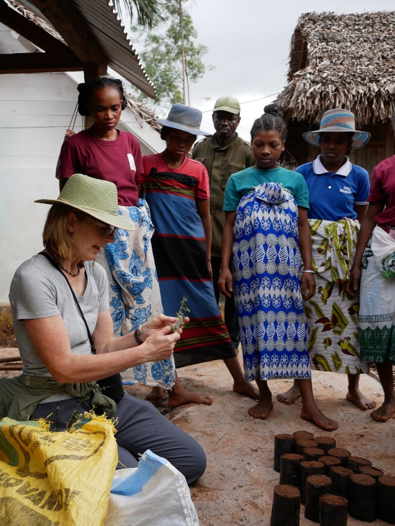 A Lady Knealt Down Talking To A Group Of Young People In Africa