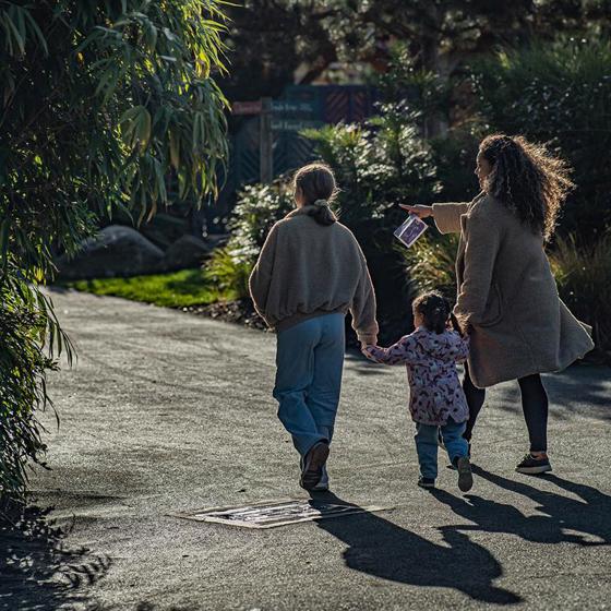 A Mum With Her Children Walking Away From The Camera In The Zoo
