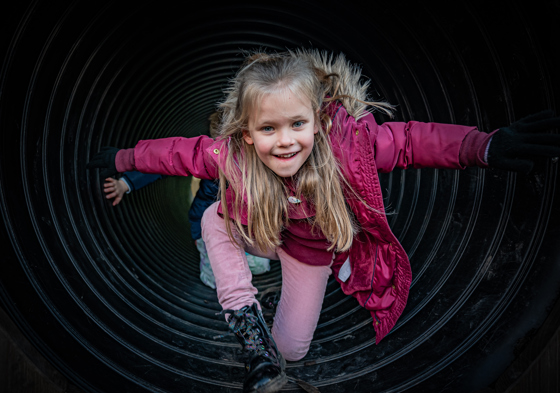 Young Girl Climbing Through A Tunnel In The Play Area